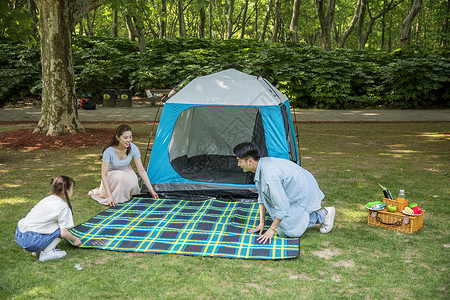 一家人郊游搭建帐篷一家人在露营时铺野餐垫背景