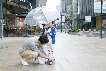 系鞋带男孩帮儿子系鞋带的父亲背景