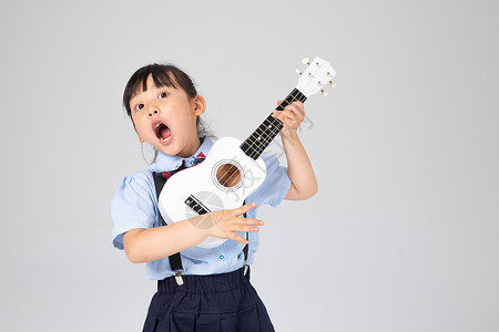 弹吉他学生弹尤克里里高声唱歌的小女孩背景