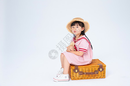 粉色旅行箱坐在旅行箱上的小女孩背景