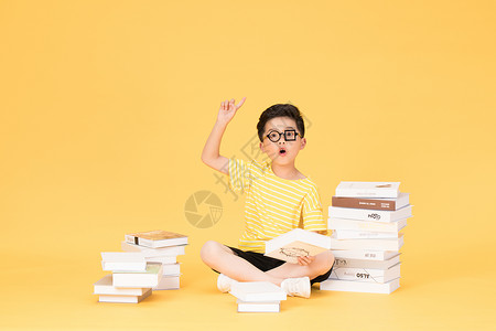 拿着钱币男孩拿着书本坐在书旁的快乐男孩背景