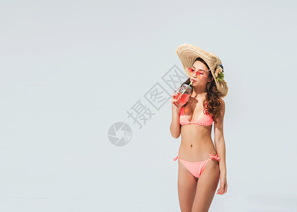 夏天冰饮沙滩穿粉色比基尼的美女头戴遮阳帽喝饮料背景