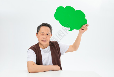 老年人拿对话框手拿绿色气泡框的老年人背景