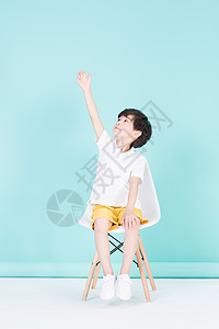 坐在凳子上举手的小男孩教育背景图片