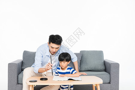 沙发上父亲教孩子写毛笔字居家高清图片素材