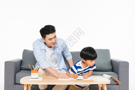 沙发上父亲辅导孩子写作业儿童高清图片素材