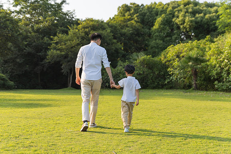 走路吃瓜的男孩公园里牵手散步父子背影背景