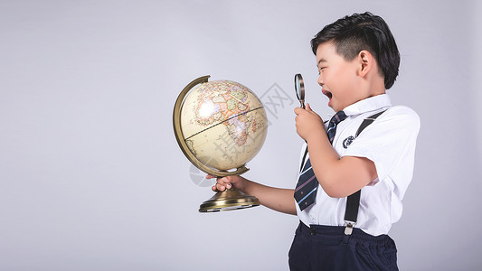 男孩用放大镜探索地球仪背景图片