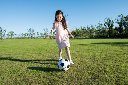 小孩子草地上踢足球背景图片