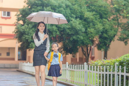 撑着雨伞孩子妈妈送孩子上学背景