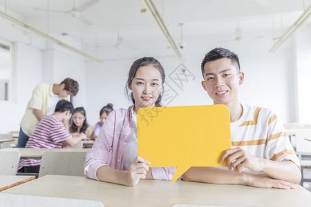 在教室里举着KT板的男女学生背景图片