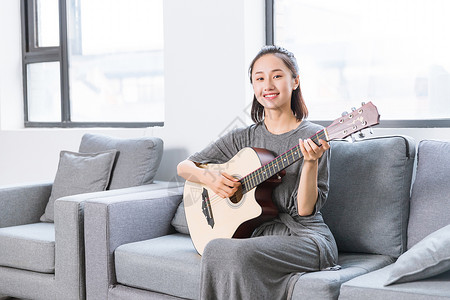 弹吉他的美女文艺青年沙发上弹吉他背景