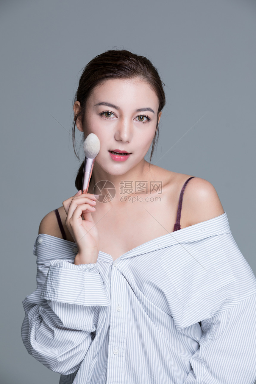 年轻美女手拿化妆刷图片