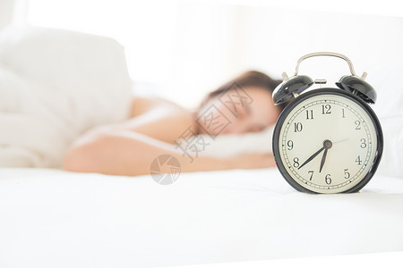 裁床年轻女性起床困难与闹钟背景