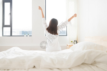 年轻女性坐床边伸展背影高清图片