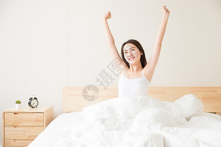 年轻女性起床床上伸展图片