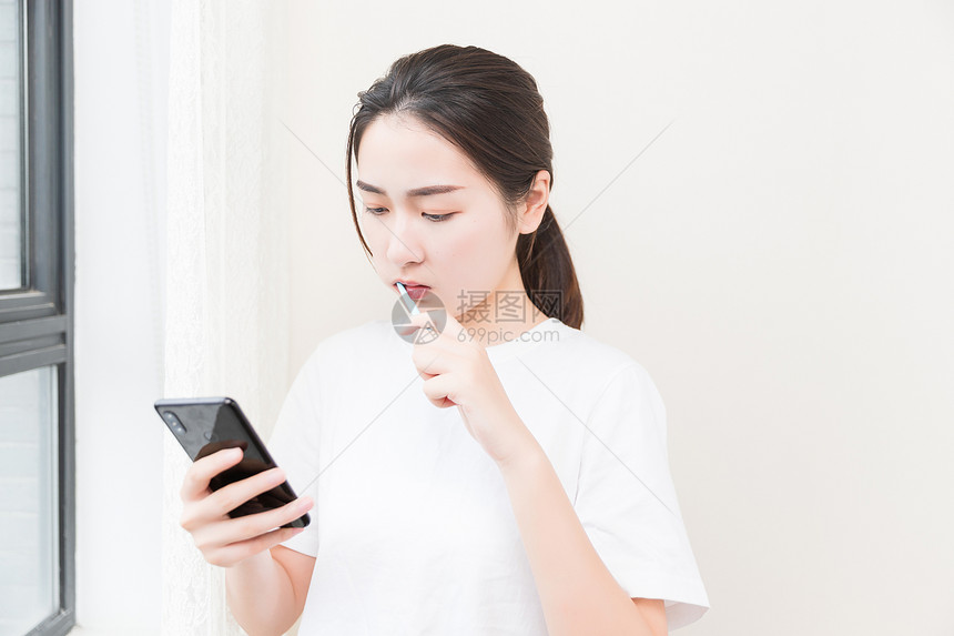 年轻女性刷牙看手机图片