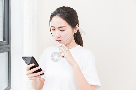 年轻女性刷牙看手机高清图片