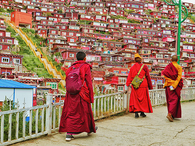 绛色色达佛学院中结伴步行的喇嘛背景