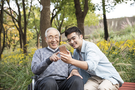 老人和年轻人敬老公园玩手机背景