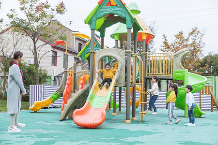 社区幼儿园户外幼师带儿童玩滑滑梯背景