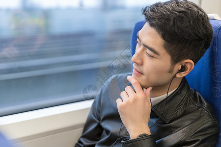 男性在高铁上听音乐出行高清图片素材
