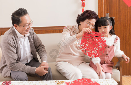 春节爷爷奶奶教孩子剪窗花背景图片