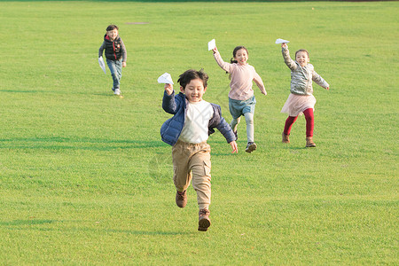 飛翔草地上玩纸飞机的孩子们背景