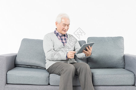 老人在沙发上看平板电脑和蔼高清图片素材