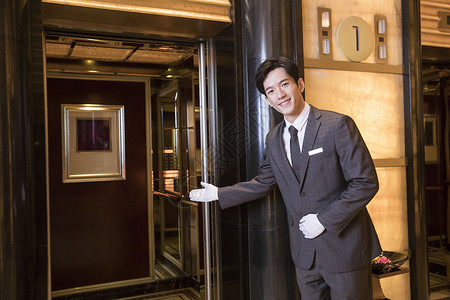物业工作酒店服务员为顾客开电梯背景