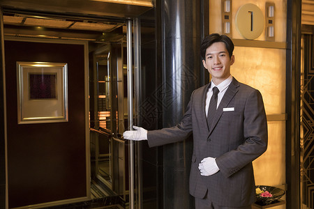 酒店服务员为顾客开电梯高清图片