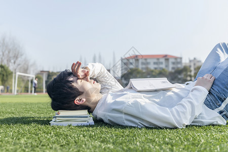 躺着看书的男孩在操场上躺着的学生背景