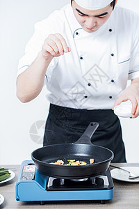 厨师撒盐炒菜调味高清图片