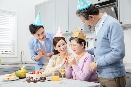 端着蛋糕妈妈一家人欢乐地庆祝生日背景