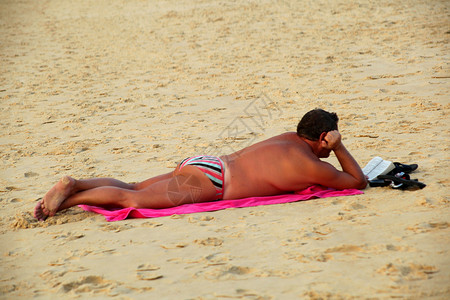 俯卧在沙滩上看书的男人背景