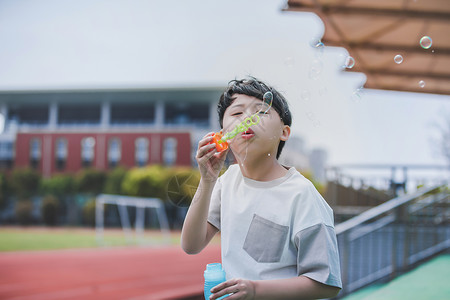 小男孩操场吹泡泡背景图片