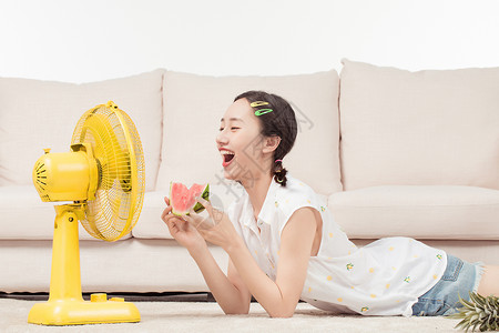 青年女子在客厅吹风扇夏天高清图片素材