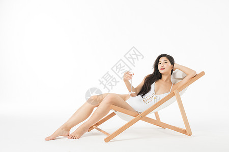 泳装美女在躺椅上喝香槟背景图片