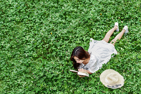 趴在草坪看书学习的女生背景图片