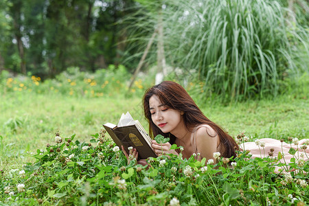 趴在花丛中看书的美女图片