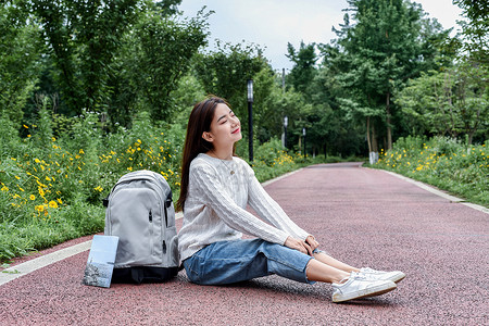 坐着休息坐在路边看书休息的女学生背景