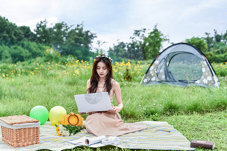 女孩岛上露营坐在草坪上用电脑的女生背景