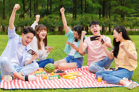 野餐垫与食物大学生野餐玩手机游戏背景