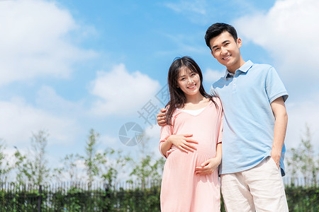 孕妇和丈夫在户外游泳池拥抱背景图片