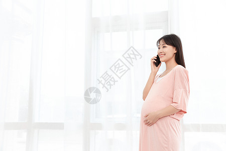 孕妇在客厅纱窗旁边使用手机打电话图片素材