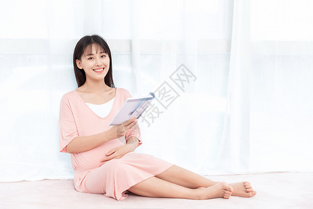 侧坐着的人孕妇在纱窗旁边侧腿坐着看书阅读背景