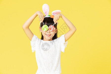 儿童发箍戴着兔耳朵的小女孩拿着糖果背景