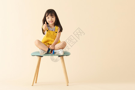 乖巧小美女小女孩坐在椅子上微笑点赞背景