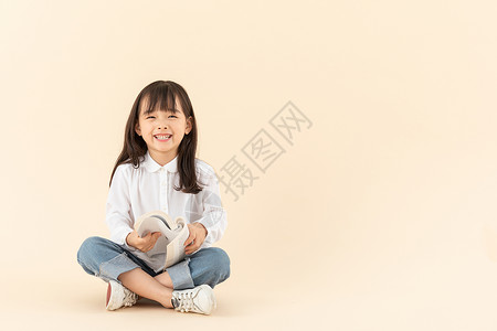 开心大笑女孩小女孩坐在地上看书背景