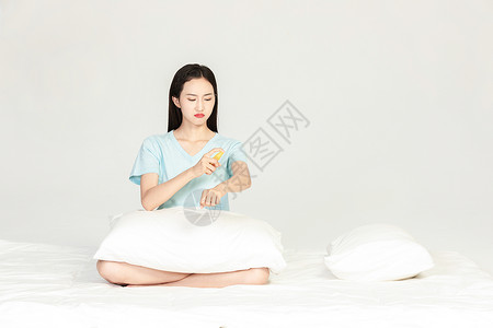 美女坐在床上用驱蚊水背景